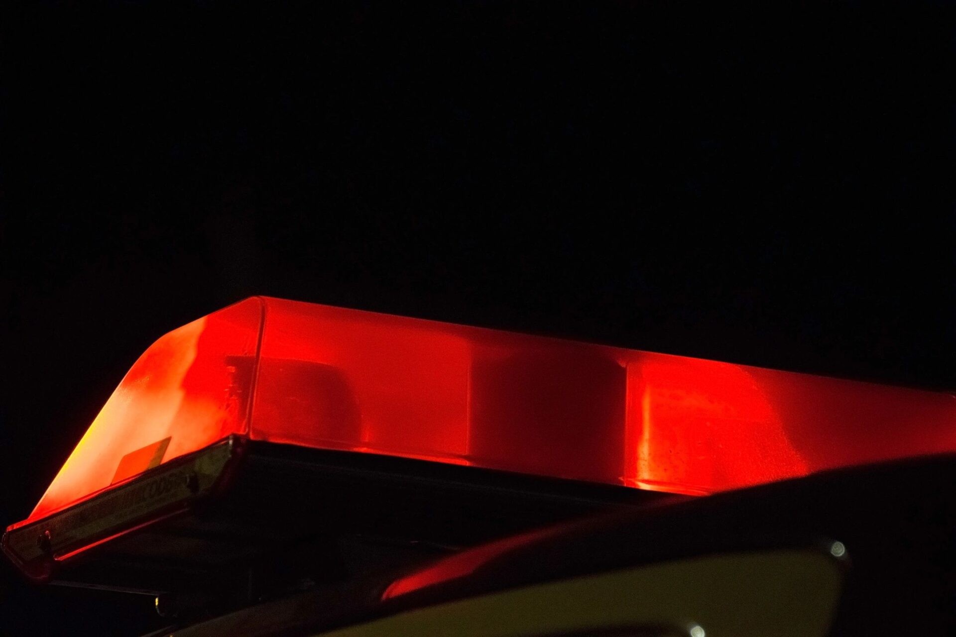 Red emergency vehicle lights glowing in the dark.